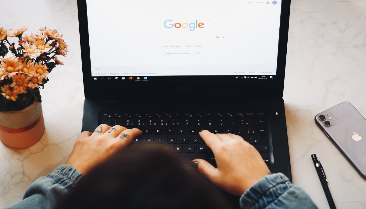 Hands type on a laptop displaying the Google homepage